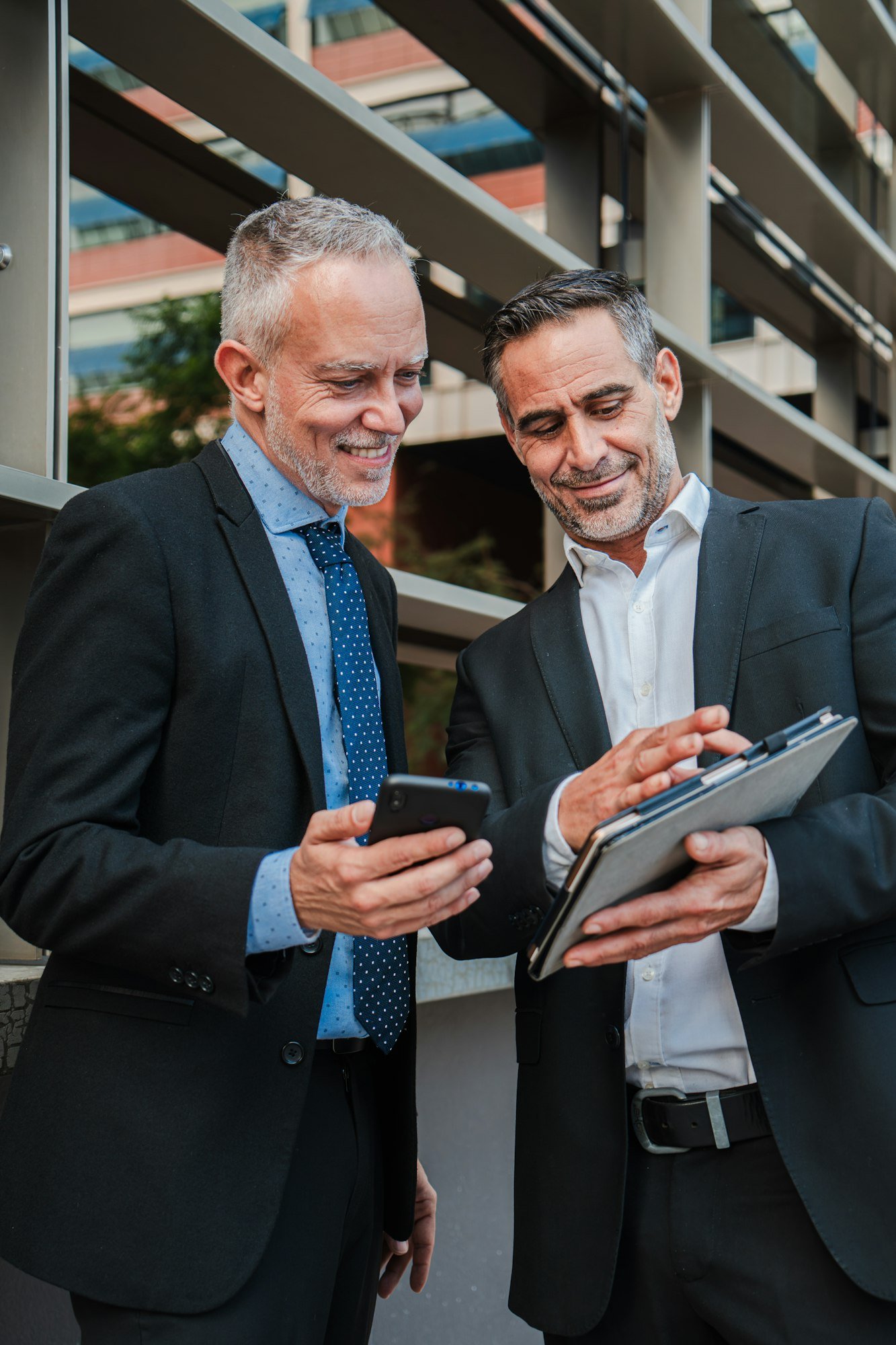 Vertical. Two professional colleagues suited up and engrossed, collaborate as they navigate data and