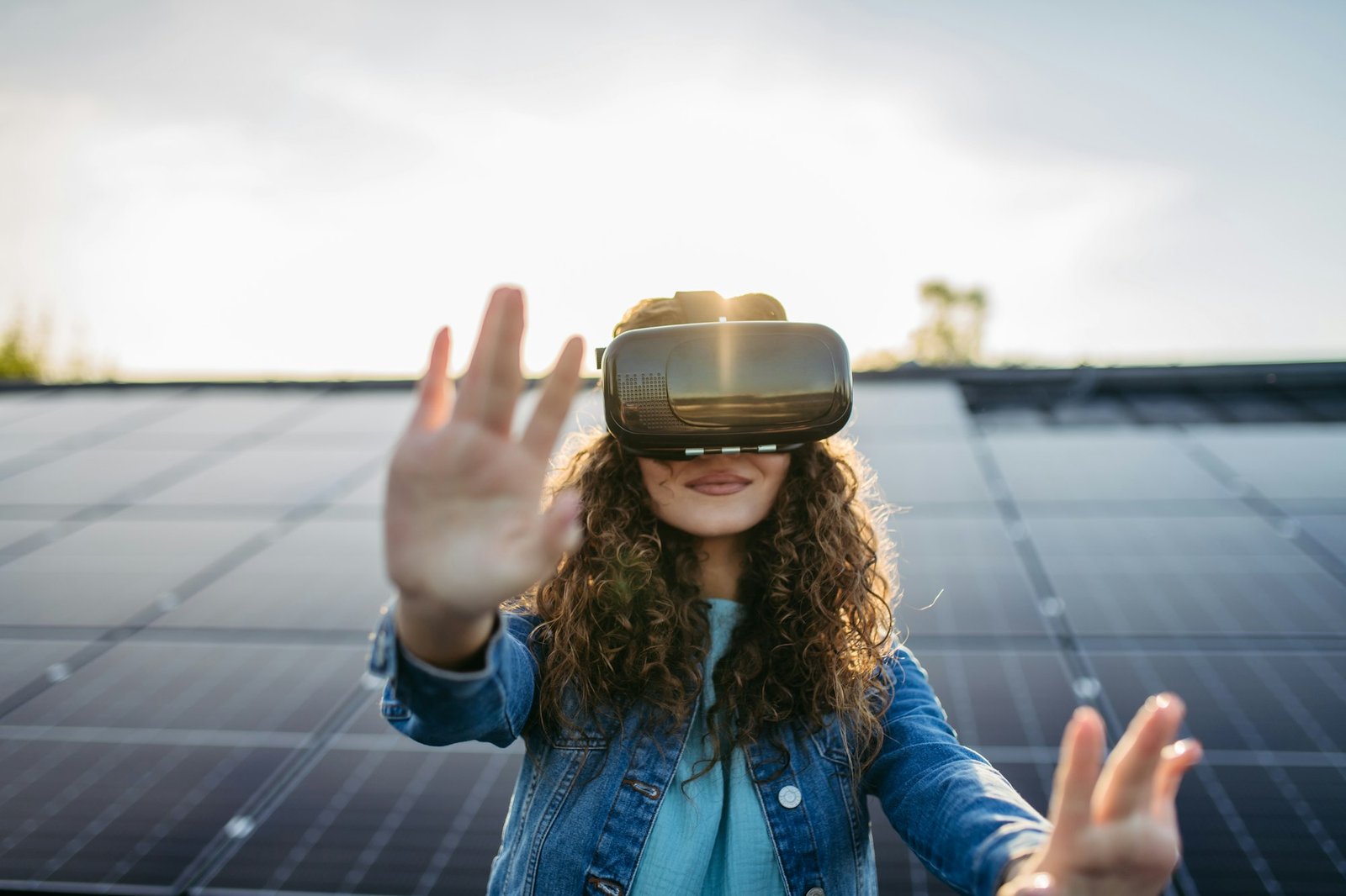 Young woman with virtual goggles on the roof with solar panels.